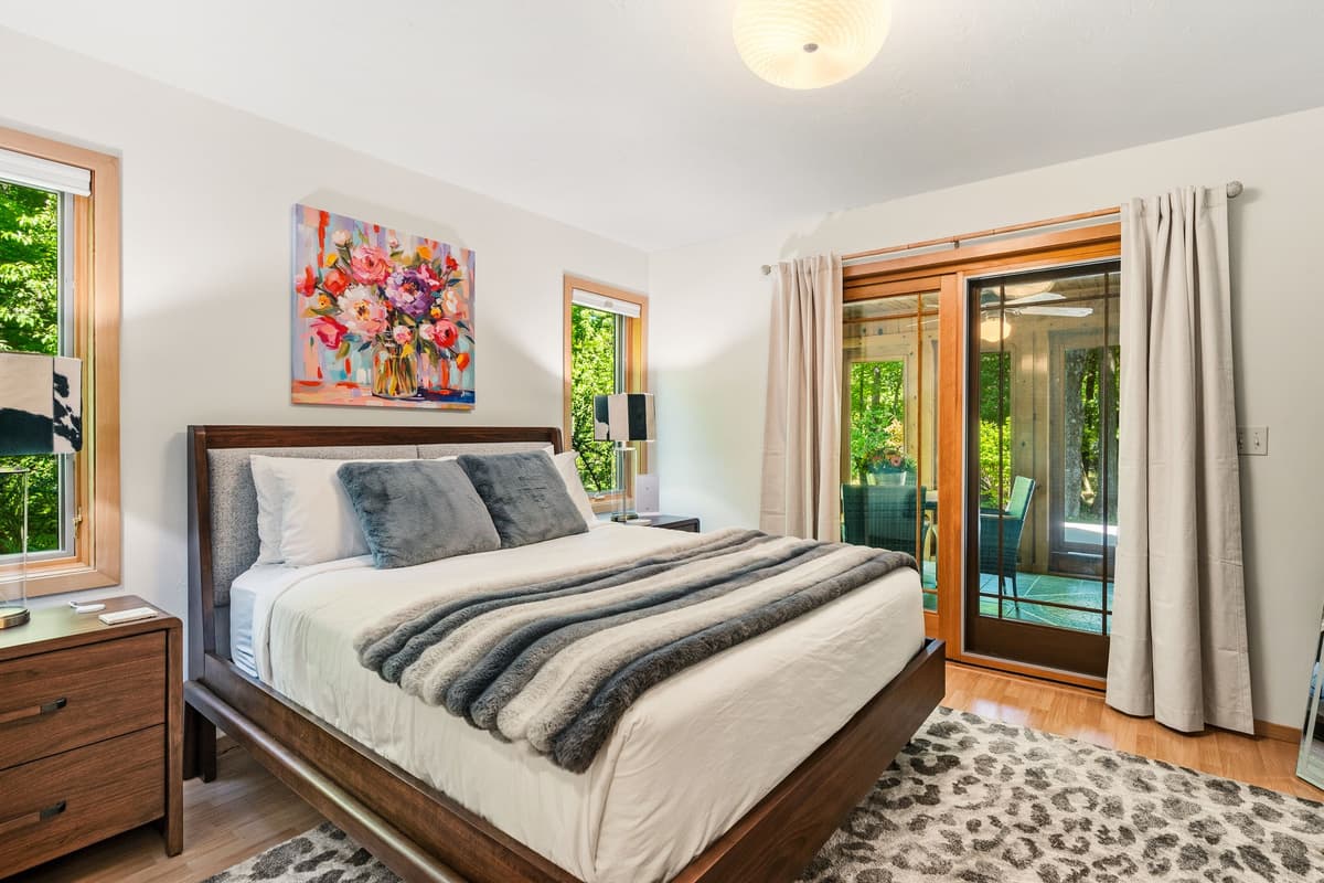 The room features a cozy queen bed with a welcoming atmosphere.
Large glass doors provide direct access to the sunroom just outside.