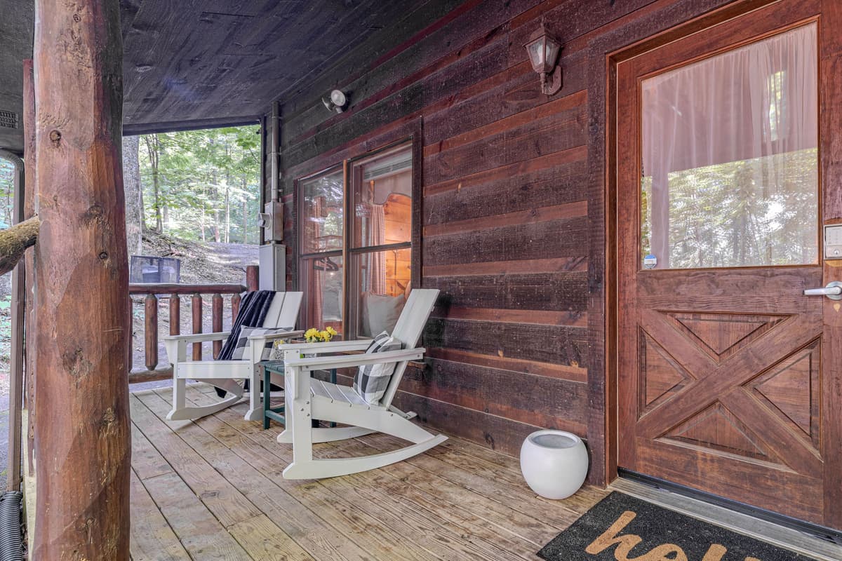 Step onto the inviting front porch of your rustic getaway, complete with comfortable Adirondack chairs and a welcoming ambiance. It's the perfect spot to relax with a drink or simply enjoy the tranquility before stepping inside your cozy retreat.