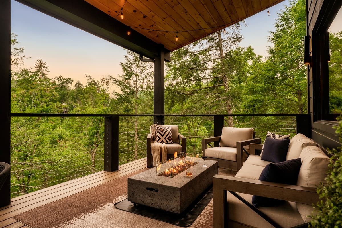 Unwind in style on this spacious outdoor deck, offering a contemporary fire table surrounded by plush seating, perfect for enjoying cool evenings under the soft glow of overhead string lights. The elevated position provides a picturesque vista of the lush