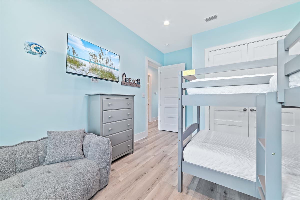 Designed with comfort and fun in mind, this inviting bedroom features a sturdy bunk bed and a plush sofa, providing versatile sleeping options. A wall-mounted television offers entertainment, making it a perfect retreat for guests of all ages.