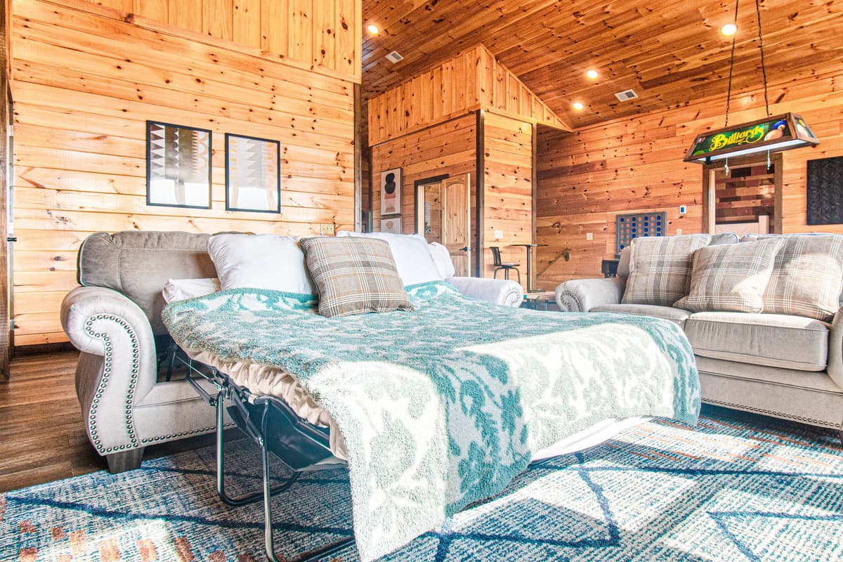 When additional sleeping space is needed, the sofa conveniently converts into a bed, making this room both comfortable and versatile for families and groups.