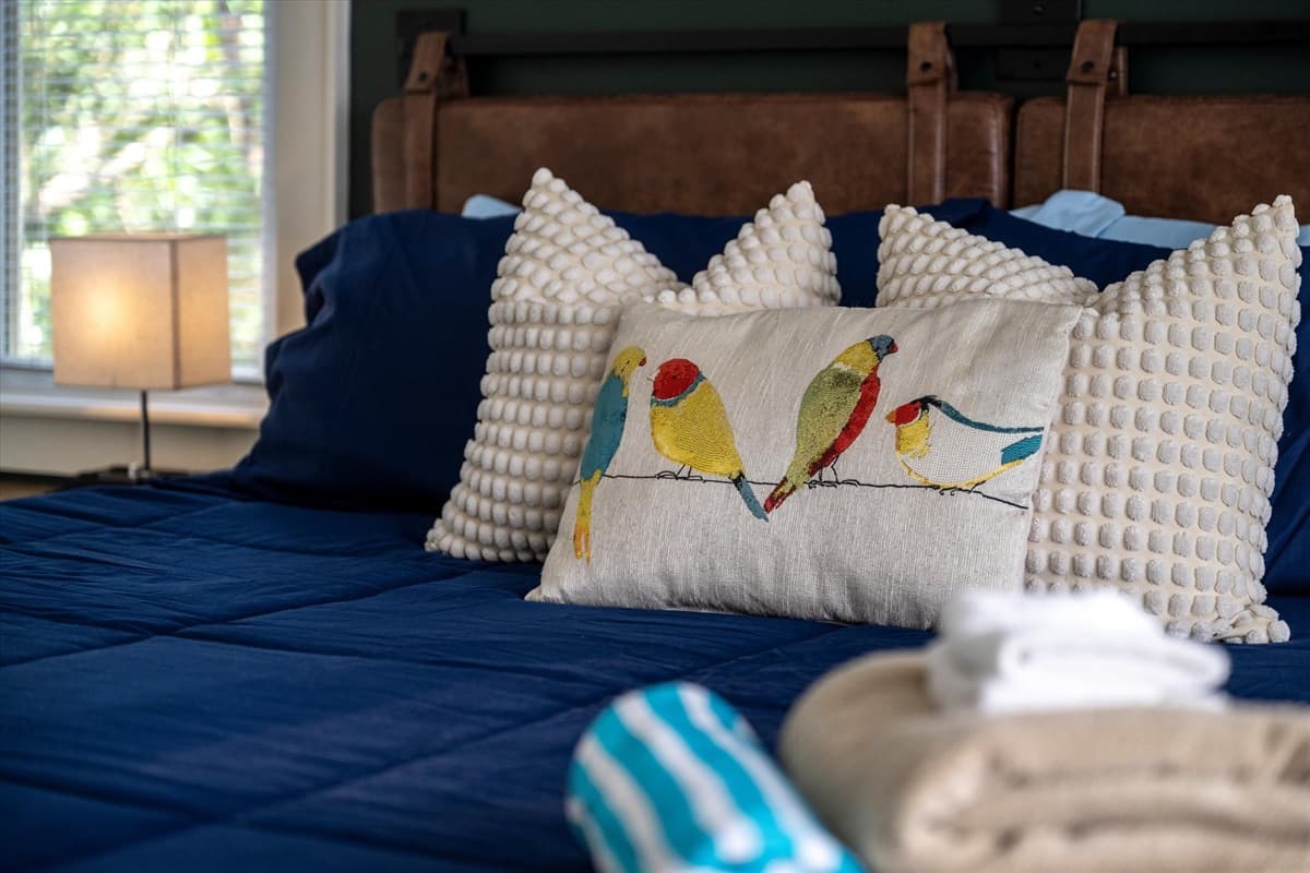 King Bedroom Close-Up with Leather Headboard, Blue Bedding, Folded Towels and Striped Hot Tub Towels