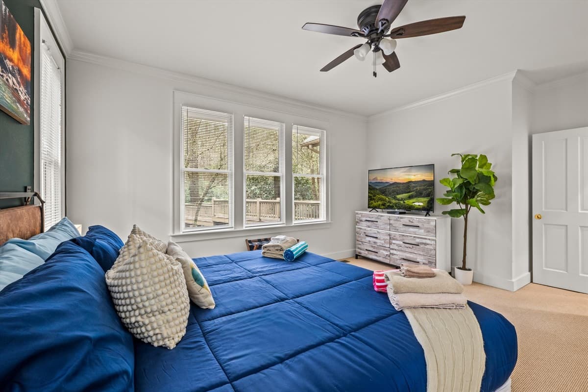 King Bedroom 1 with Blue Comforter, Ceiling Fan, TV and Large Bright Windows