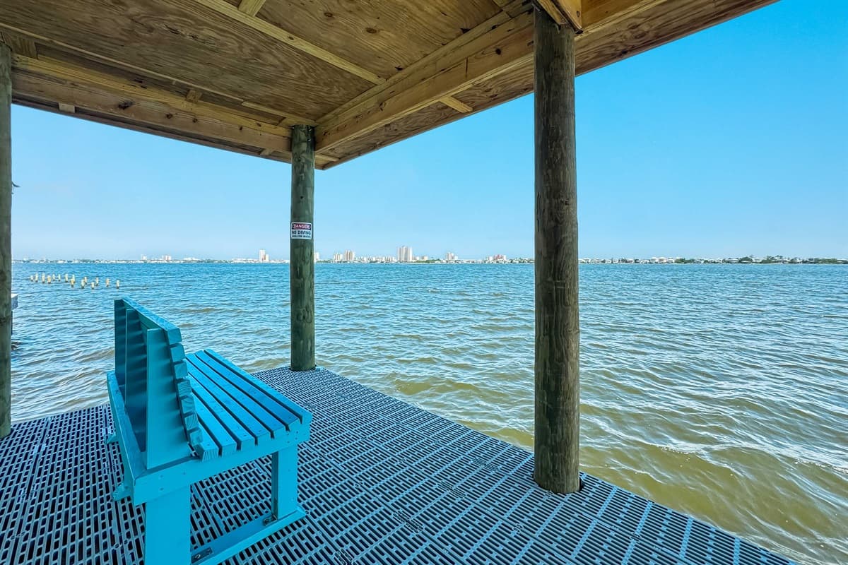 Enjoy peaceful waterfront views from this covered private dock, complete with a comfortable bench for relaxation.