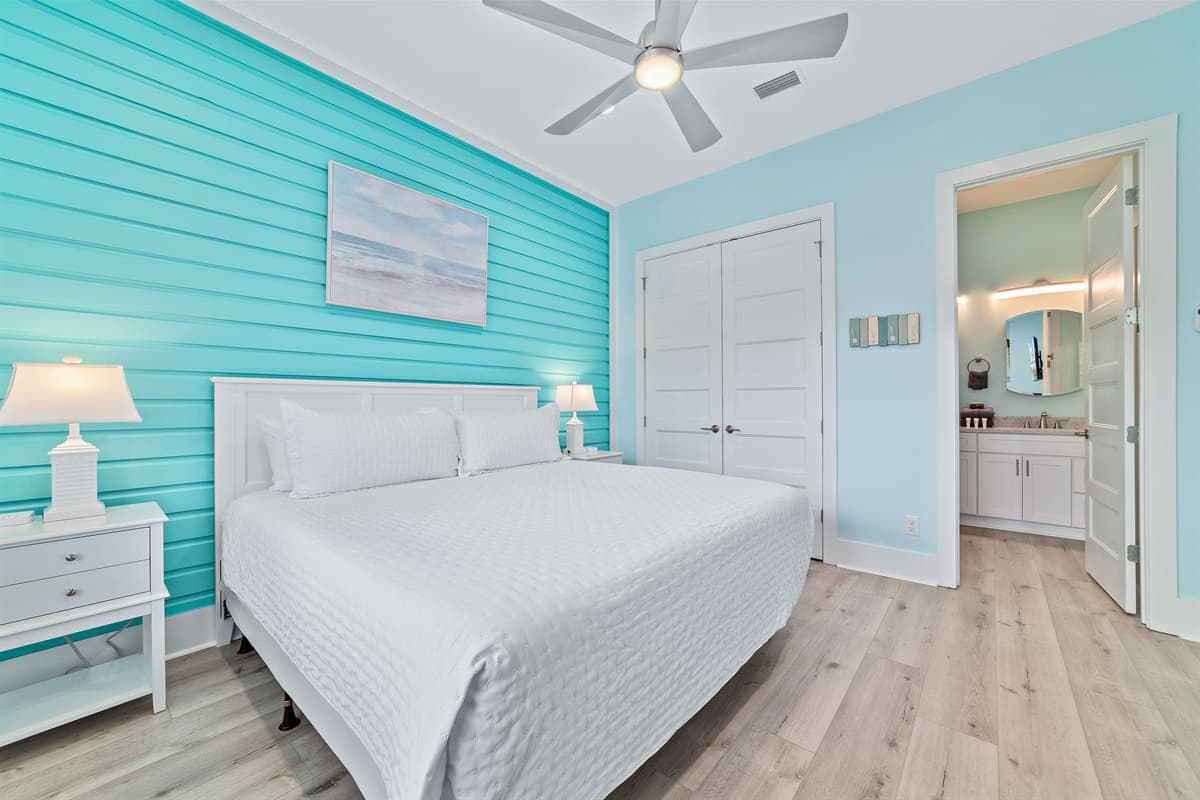 This bright bedroom features a comfortable queen-sized bed with a vibrant blue shiplap accent wall, and direct access to a private bathroom.