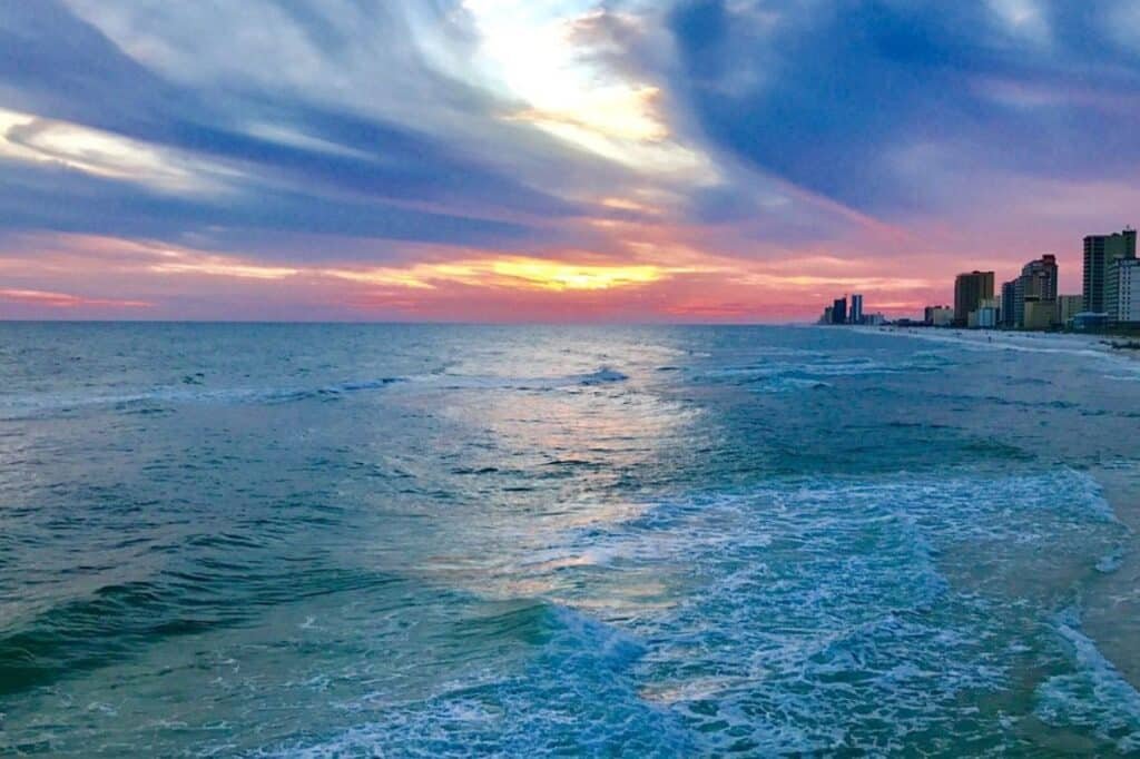 People walking along the sandy beach and pier in Gulf Shores Alabama on a sunny day
