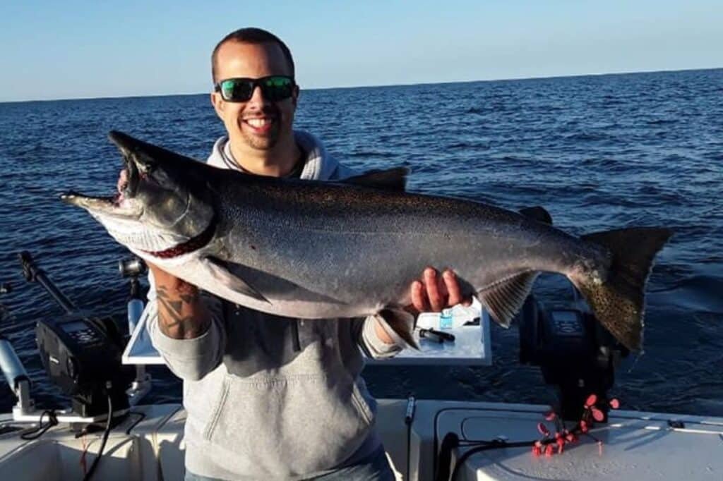 Angler casting a line from a boat on calm Door County waters at sunrise
