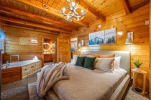 Retreat to this stunning log cabin bedroom, offering a luxurious king bed and an en-suite bathroom with a soaking tub, perfect for a truly relaxing and indulgent stay.