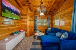 Relax in the heart of this charming cabin, where a warm stone fireplace and comfortable furnishings invite you to unwind after a day of adventures. The cozy living area, complete with a large screen for entertainment, creates a perfect gathering spot for y