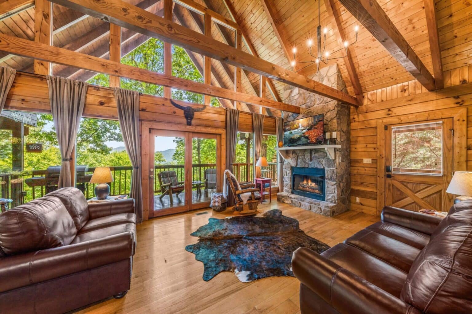 Step into rustic paradise in our cabin's great room, where cathedral windows frame nature's beauty, wood beams exude charm, and a roaring fireplace beckons lounging luxury.