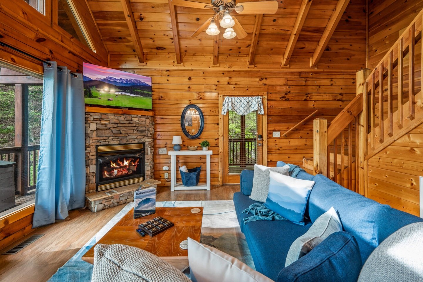 Relax and unwind in our inviting living room, featuring a cozy fireplace for chilly evenings and a large flat-screen TV for entertainment. Surrounded by warm wooden walls and offering glimpses of the outdoors through charming windows, this space provides t